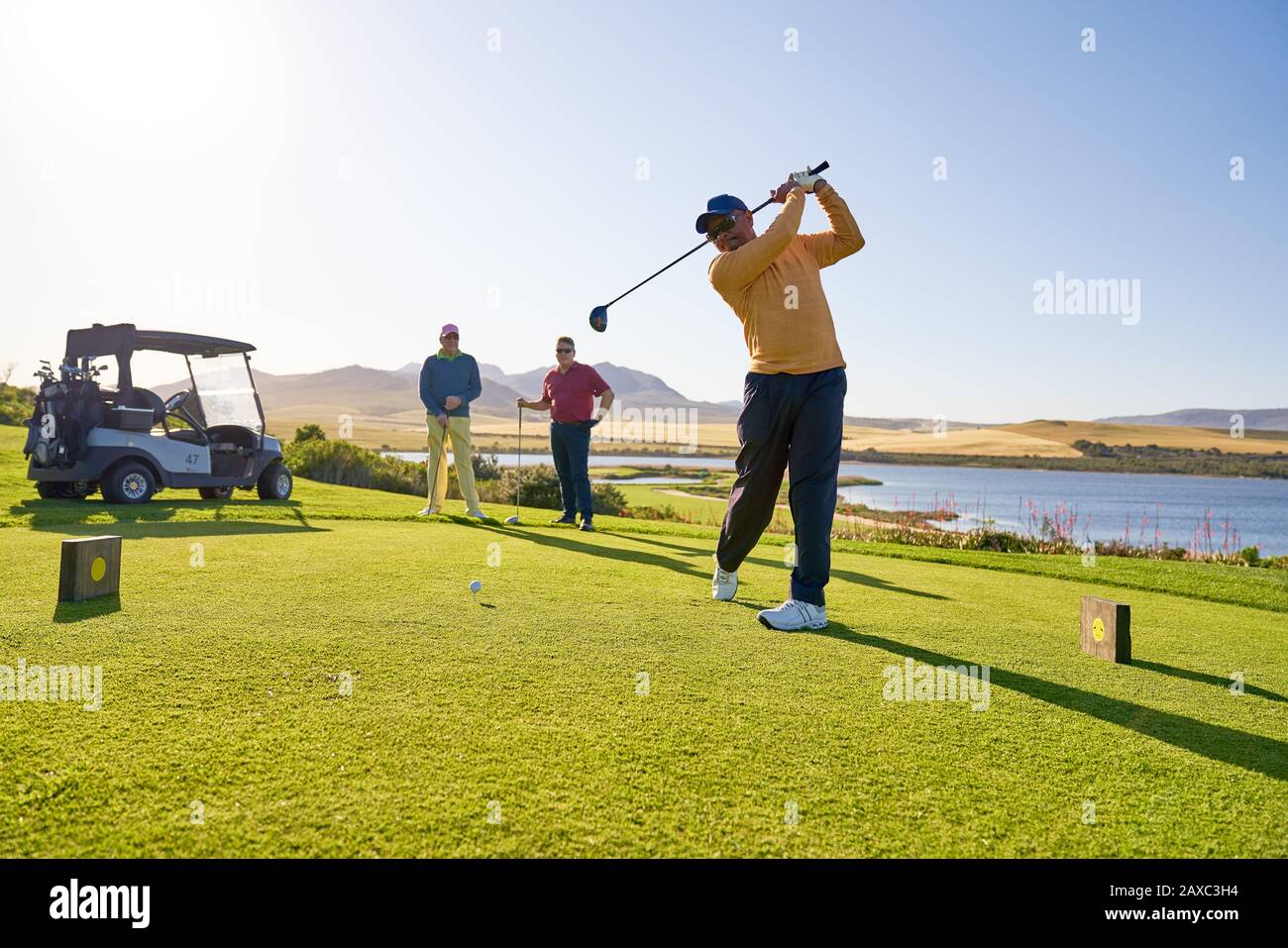 Männlicher Golfer, der an der sonnigen Golf-T-Box abzweigte Stockfoto