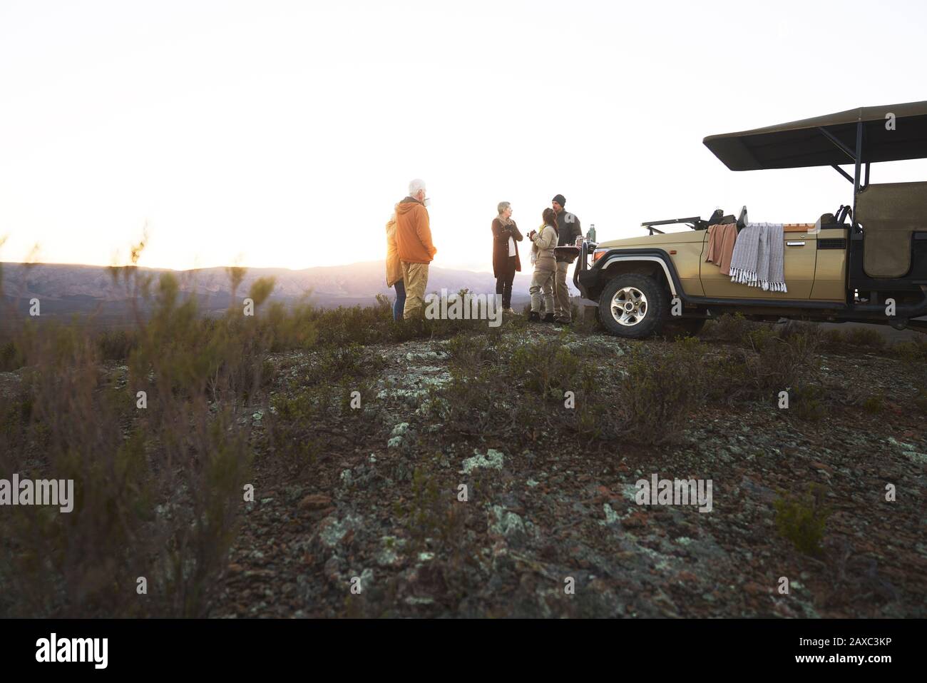 Safari-Tour-Gruppe, die Tee vor dem Geländewagen bei Sonnenaufgang trinkt Stockfoto