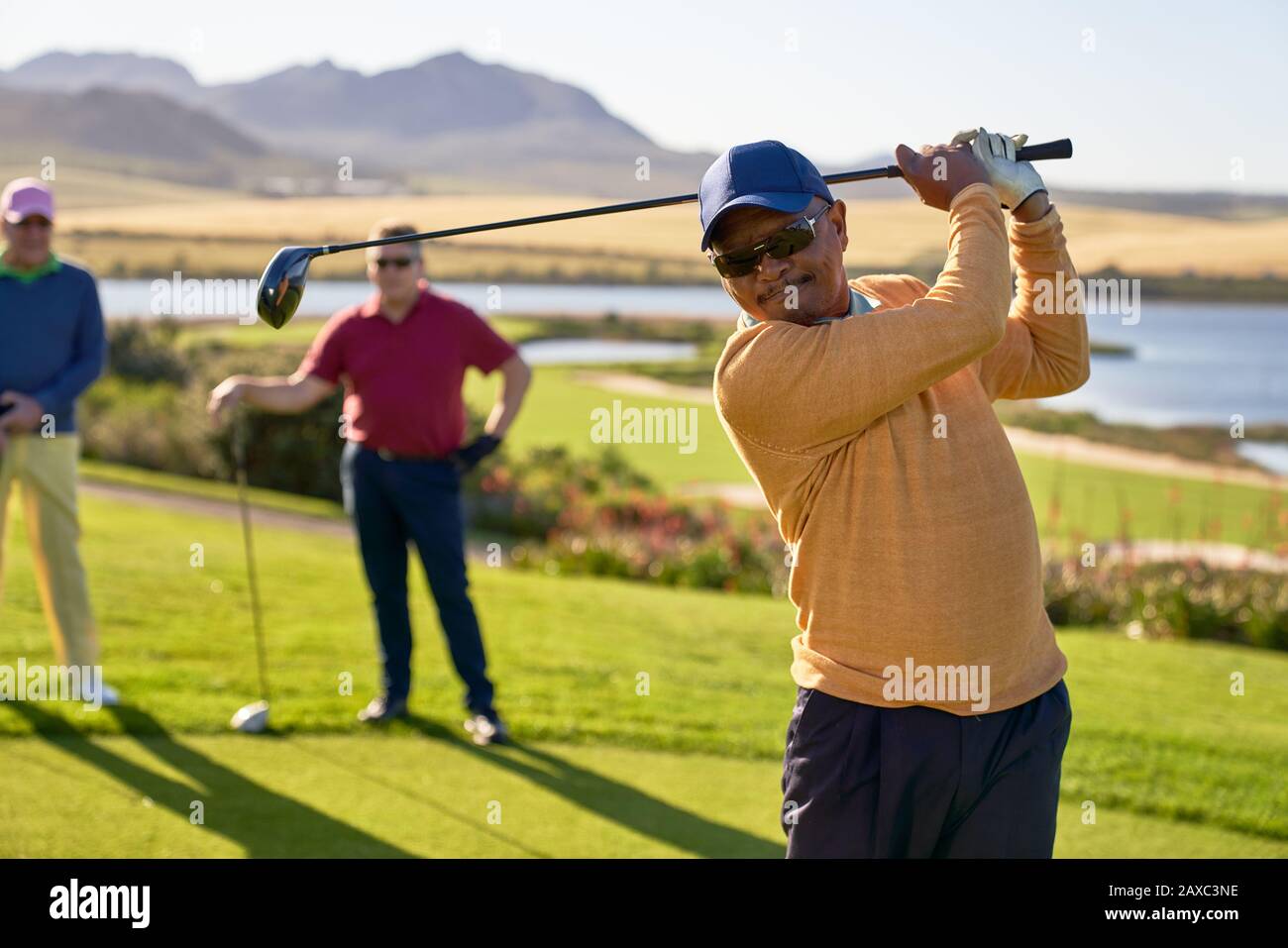 Reifer männlicher Golfer, der an der sonnigen Kiste abzweigte Stockfoto