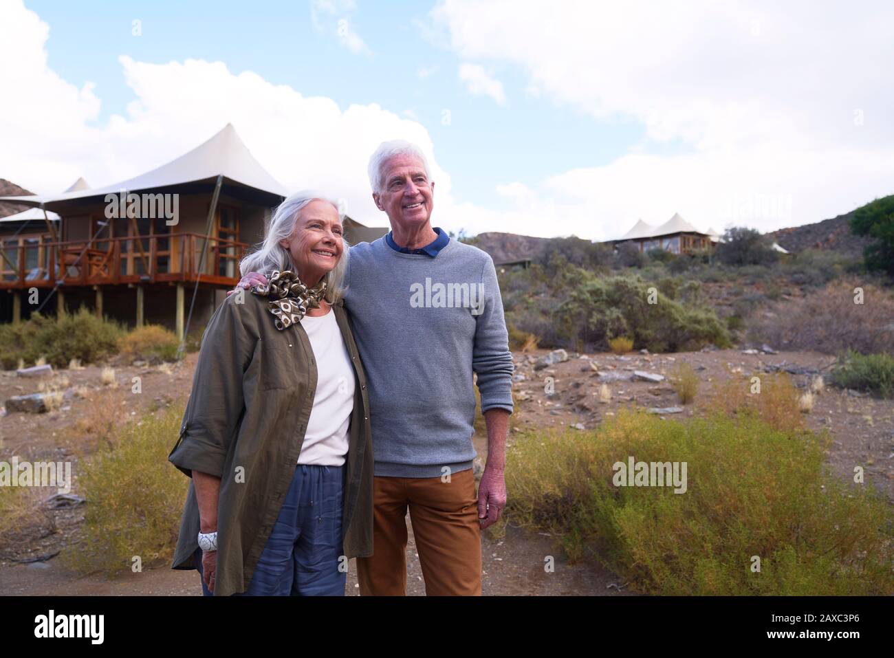 Glückliches älteres Paar vor der Safarihütte Stockfoto