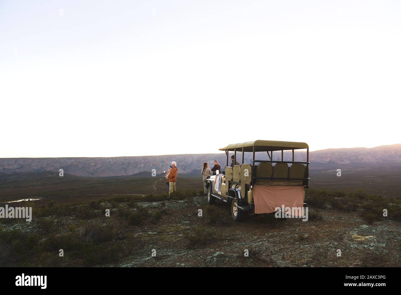 Safari-Tour-Gruppe und Geländewagen auf abgelegenen Hügeln bei Sonnenaufgang Stockfoto