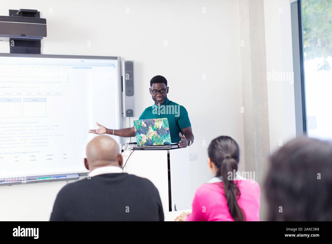 Lehrer der männlichen Community unterrichten Unterricht am Laptop und Projektionsleinwand im Klassenzimmer Stockfoto
