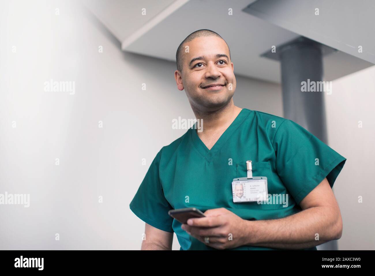 Lächelnder männlicher Chirurg mit Smartphone Stockfoto