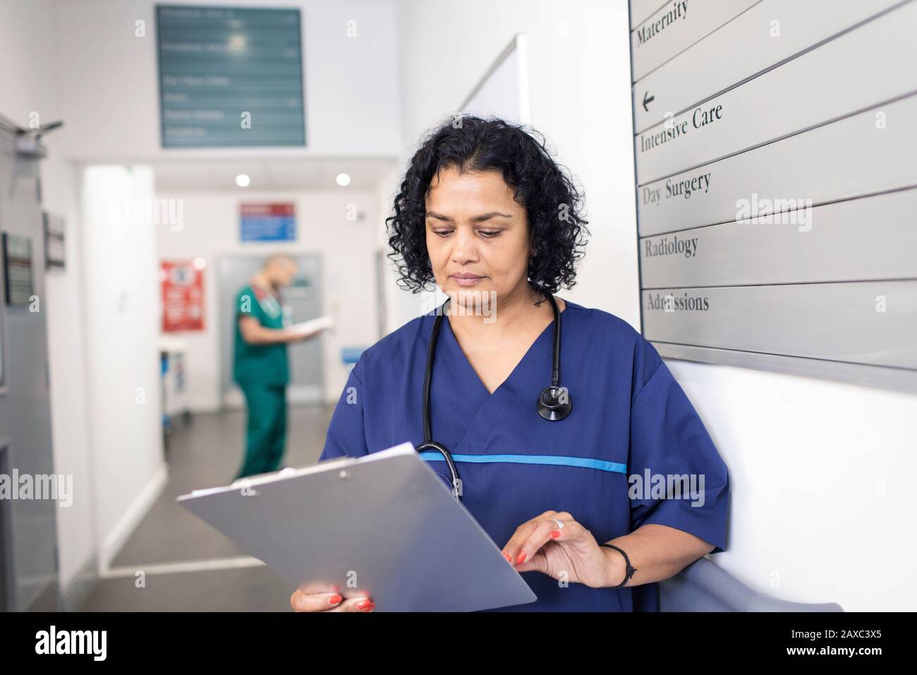 Ärztin mit ärztlicher Dokumentation, die im Krankenhauskorridor Runden macht Stockfoto