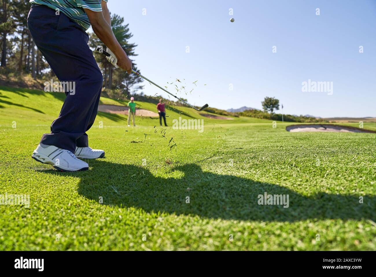 Männlicher Golfer, der auf einem sonnigen Golfplatz einen Schuss abschießt Stockfoto