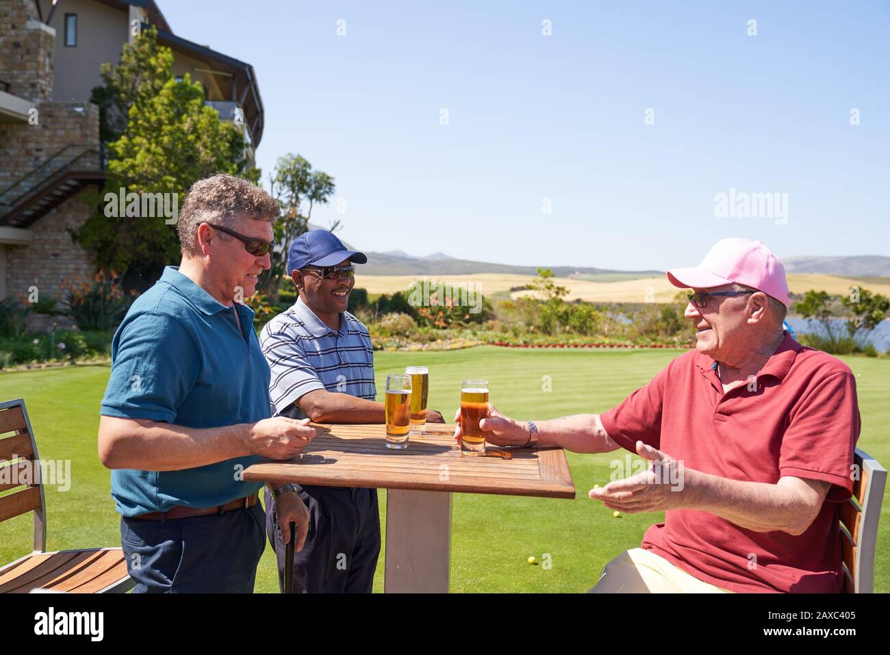 Glückliche reife männliche Golfer trinken Bier im sonnigen Golfplatzenklubhaus Stockfoto