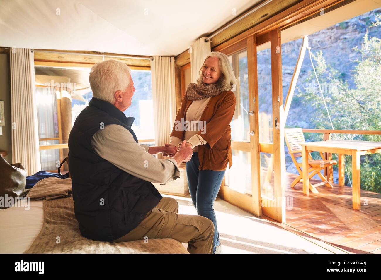 Glückliches älteres Paar, das die Hände im Hotelzimmer der Safari-Lodge hält Stockfoto