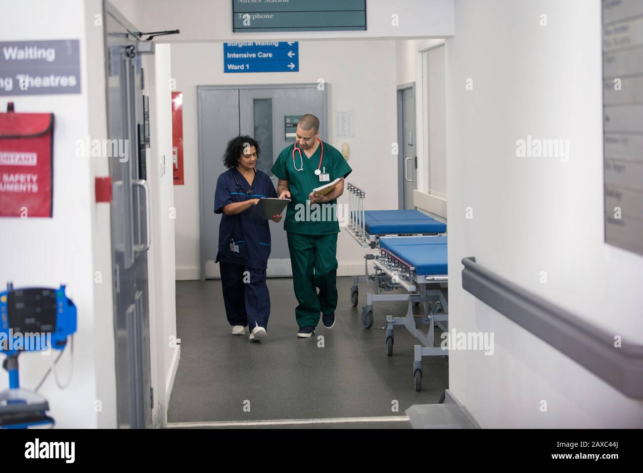 Arzt und Chirurg diskutieren über die medizinische Karte und gehen im Krankenhauskorridor Stockfoto