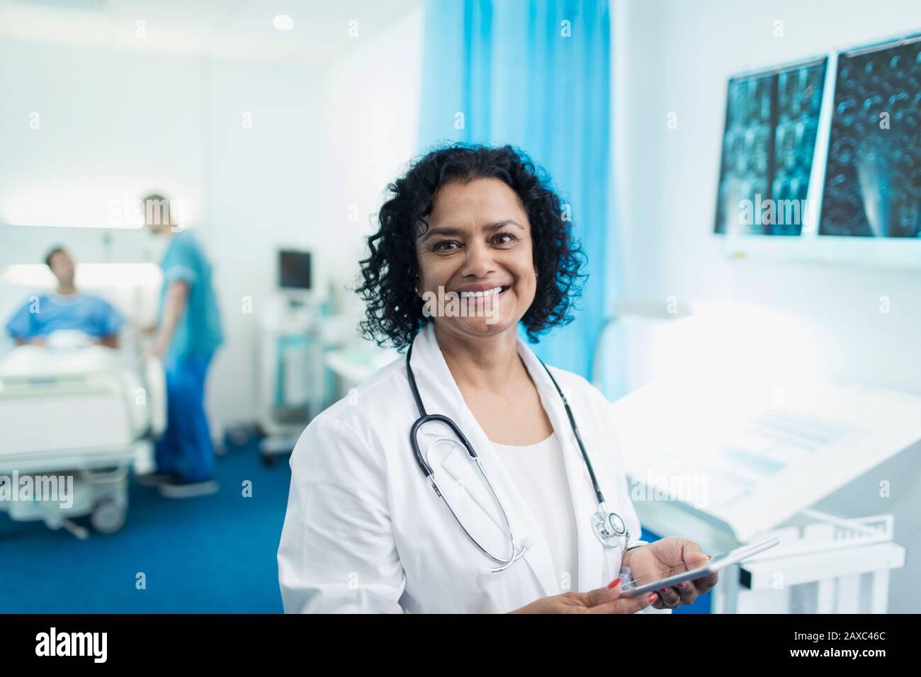 Lächelnde, selbstbewusste Ärztin im Portrait, die digitale Tablette im Krankenhauszimmer verwendet Stockfoto