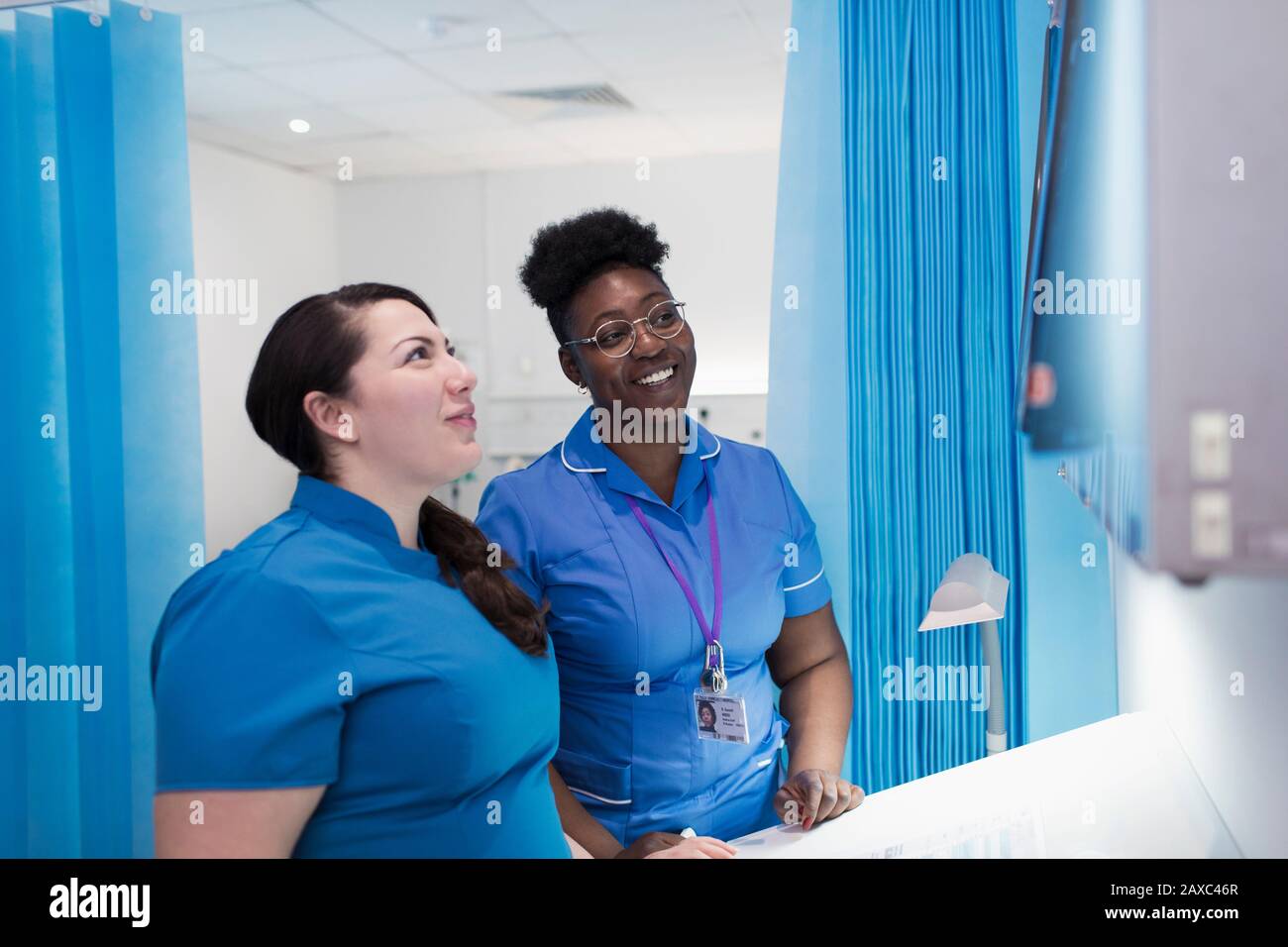 Weiblicher Arzt und Krankenschwester, die Röntgenaufnahmen im Krankenhauszimmer untersuchen Stockfoto