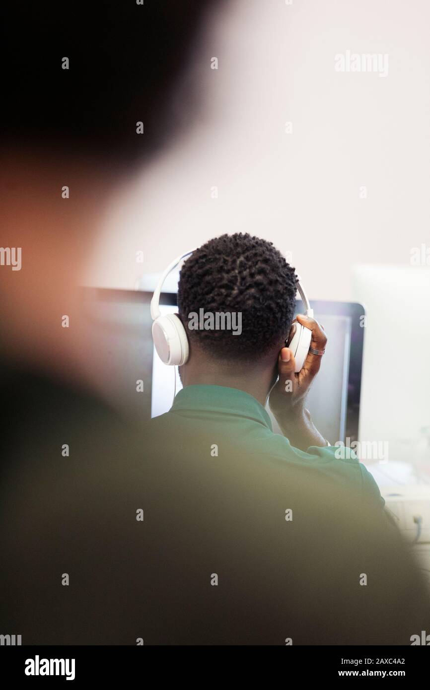 Student der männlichen Community mit Kopfhörern am Computer Stockfoto