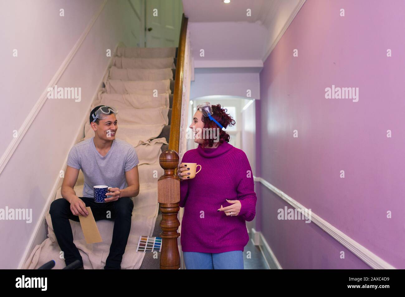 Glückliches Paar, das sich wieder schmückt und Kaffee auf der Treppe trinkt Stockfoto