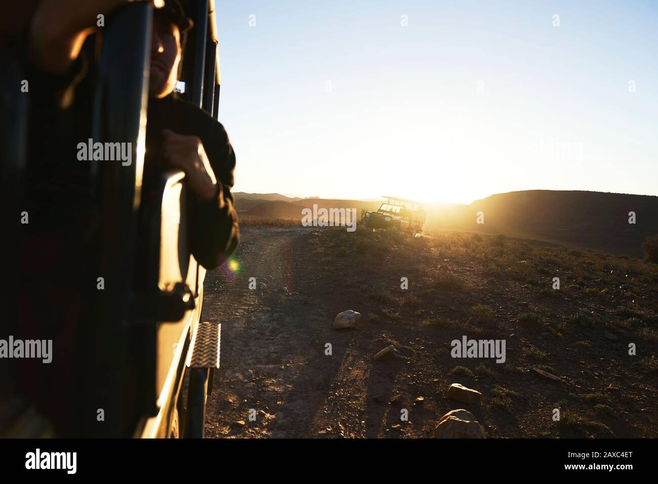 Geländewagen mit Safari, die bei Sonnenaufgang auf der Felsenmautstraße fahren Stockfoto
