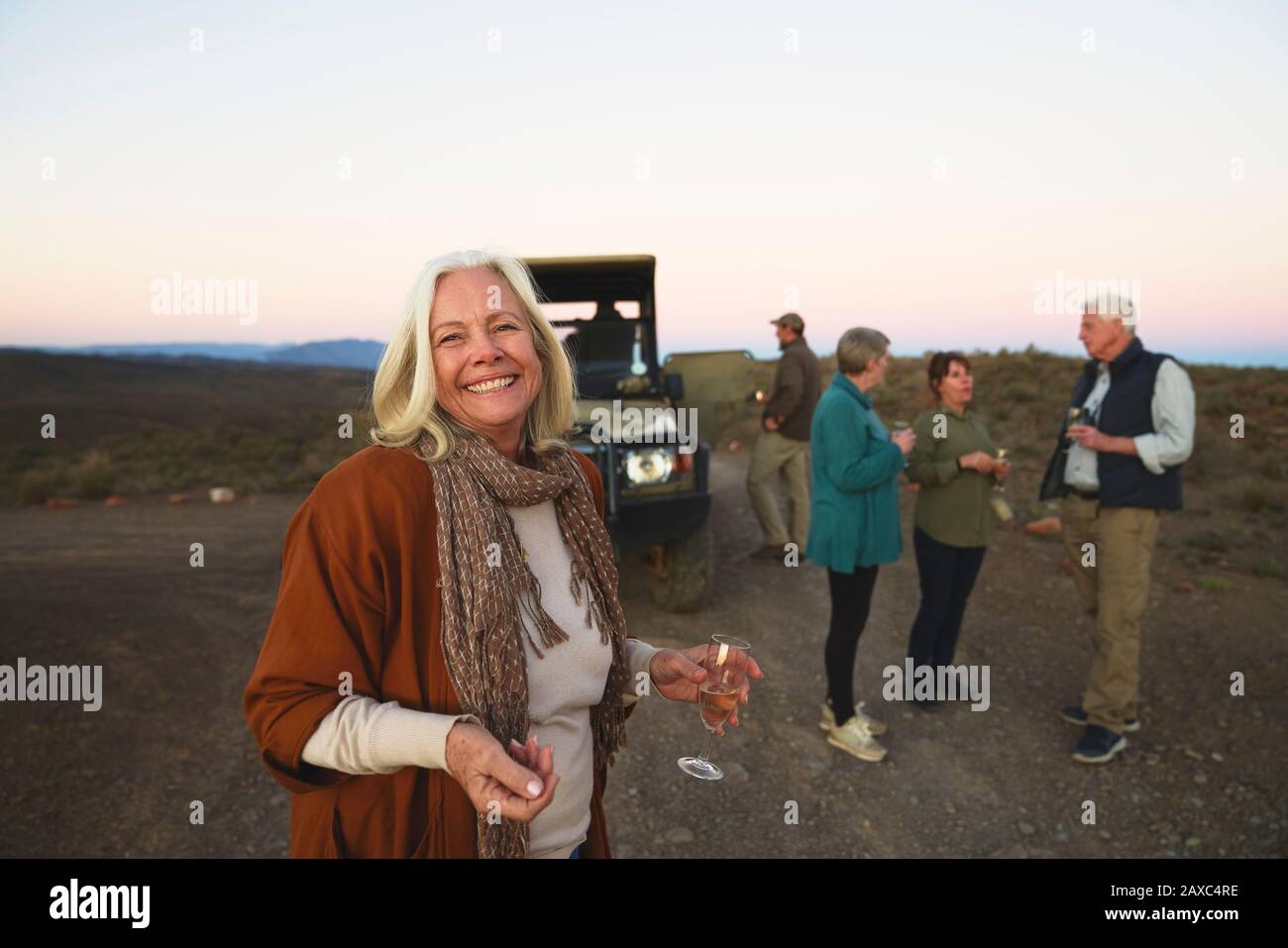Portrait fröhliche ältere Frau, die Champagner auf Safari trinkt Stockfoto