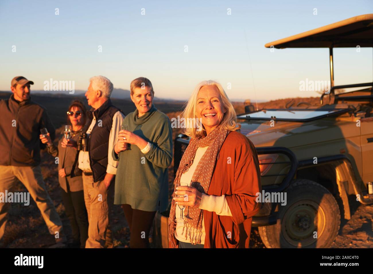 Portrait fröhliche ältere Frau auf Safari, die Champagner mit Freunden trinkt Stockfoto