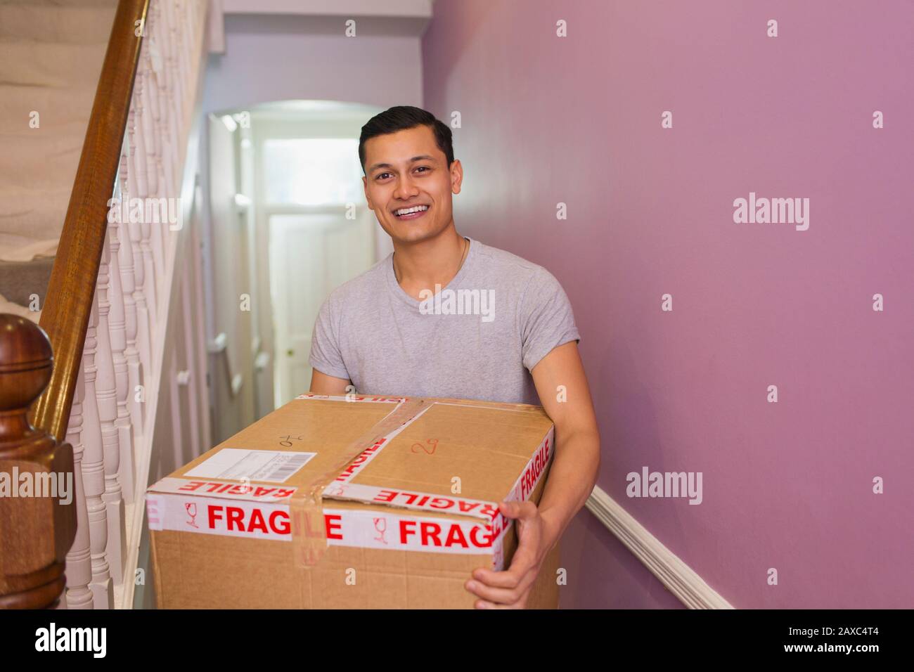 Portrait glücklicher Mann mit bewegter Schachtel im Korridor Stockfoto