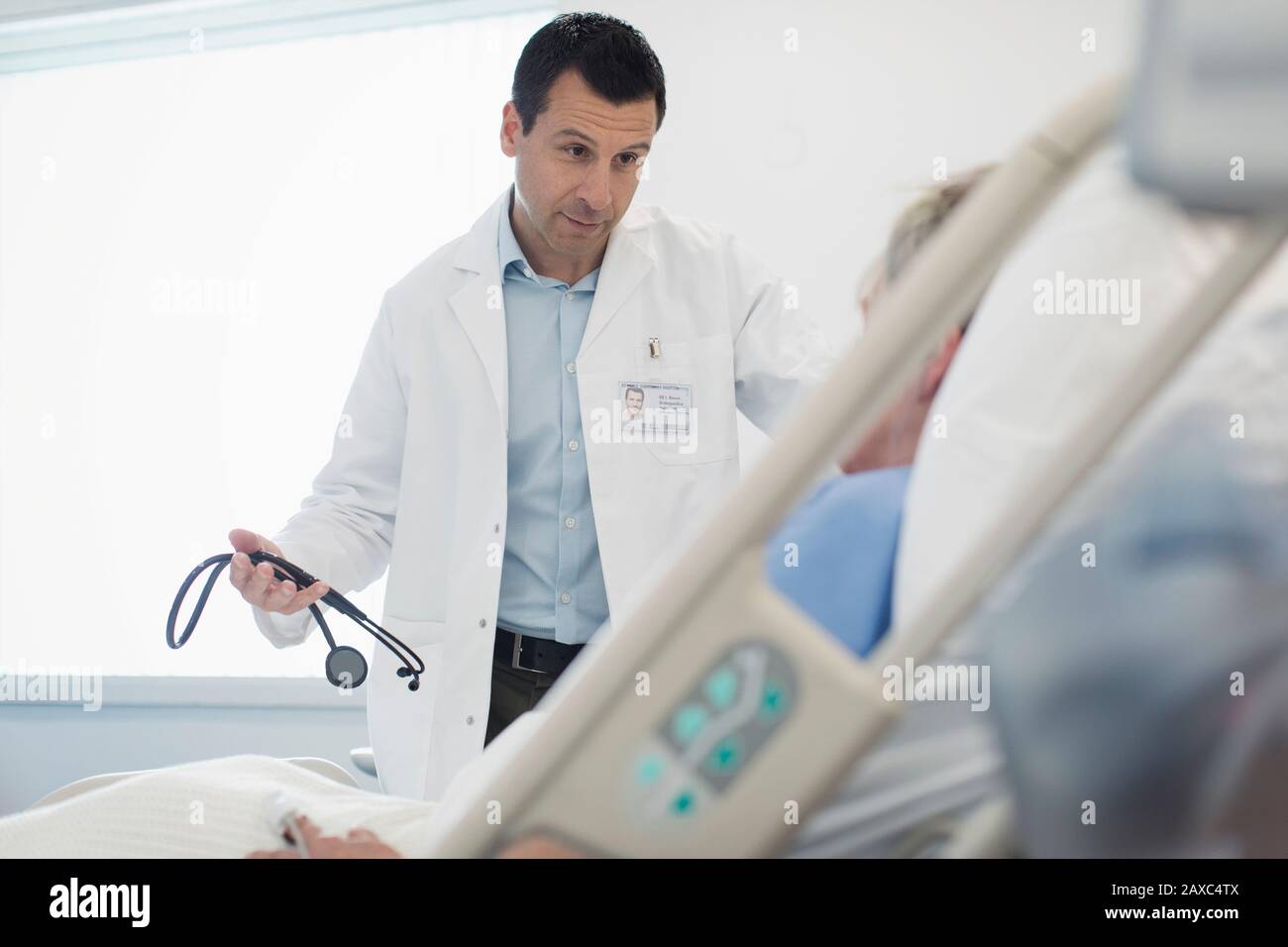 Arzt macht Runden und spricht mit dem Patienten im Krankenhauszimmer Stockfoto
