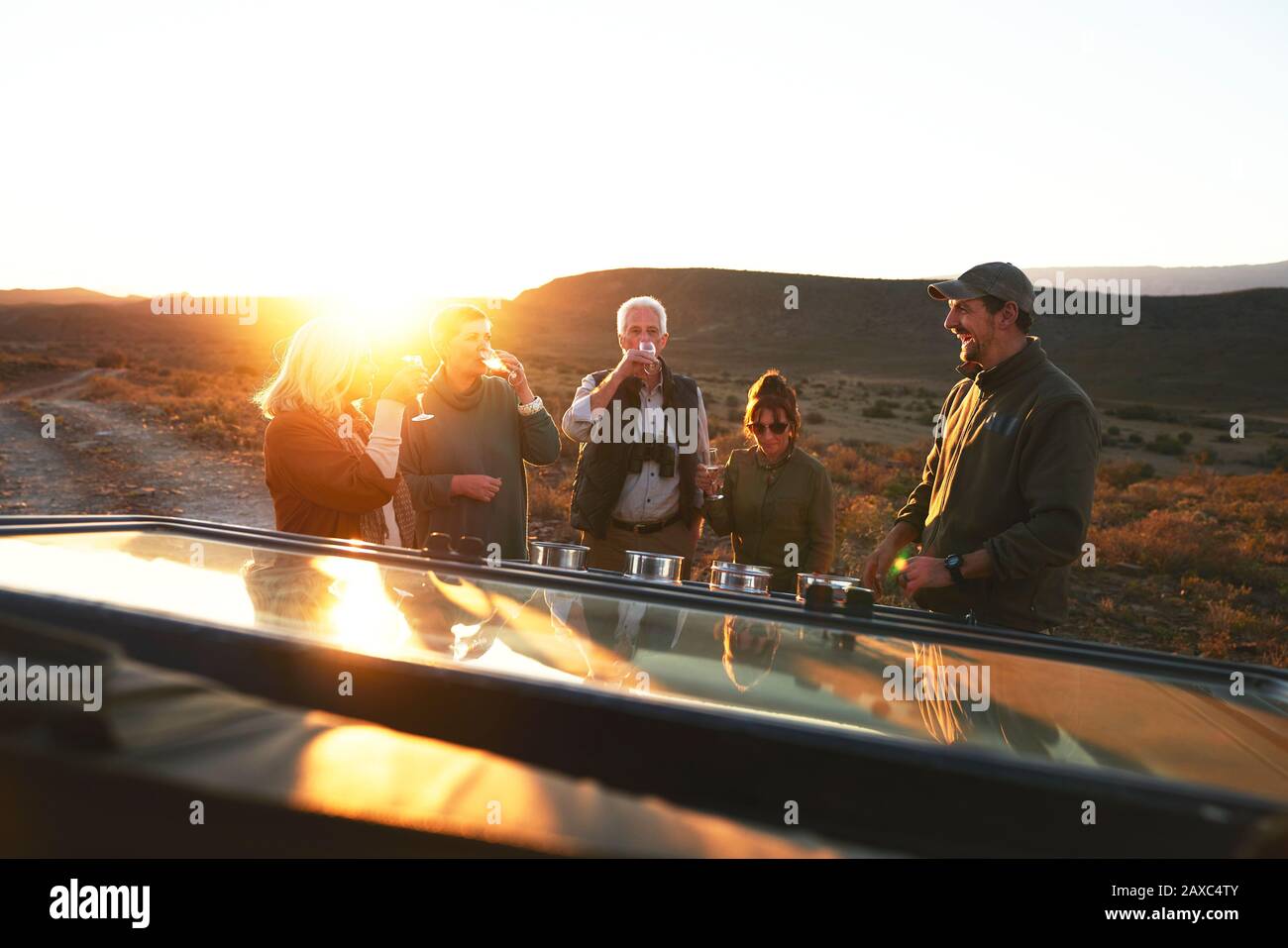 Safari-Tour-Gruppe, die Champagner bei Sonnenuntergang trinkt Stockfoto