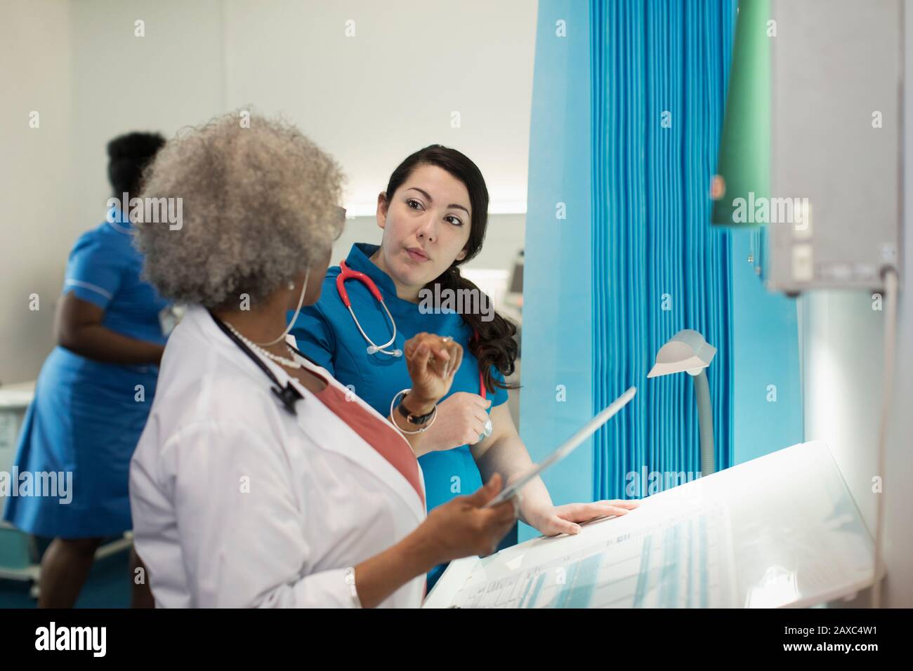 Ärztin und Krankenschwester mit digitaler Tablette im Krankenhauszimmer Stockfoto