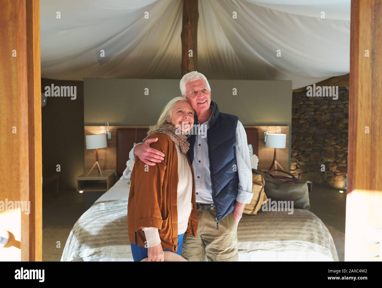 Portrait glückliches älteres Paar, das sich im Hotelzimmer der Safari-Lodge umarmt Stockfoto