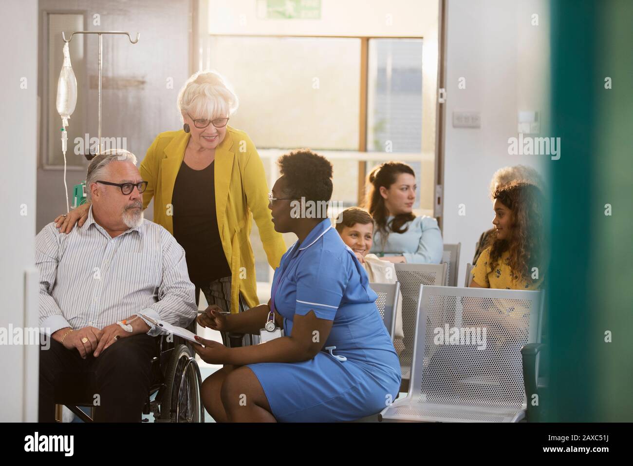Weibliche Krankenschwester im Rollstuhl im Klinikfoyer mit einer älteren Patientin sprechen Stockfoto