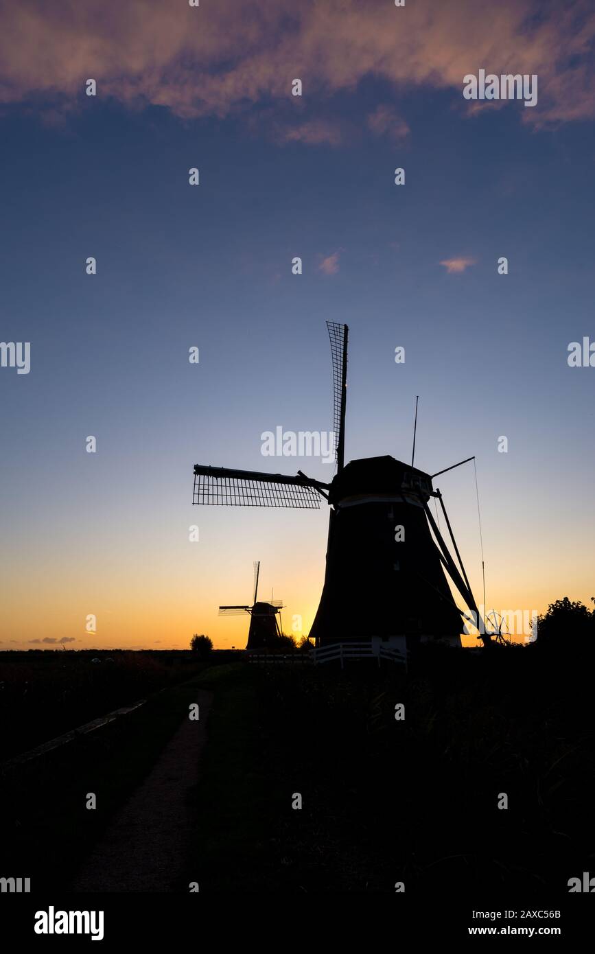 Wunderschönes Landschaftsbild von zwei Windmühlen, die sich gegen den Abendhimmel abstachen Stockfoto