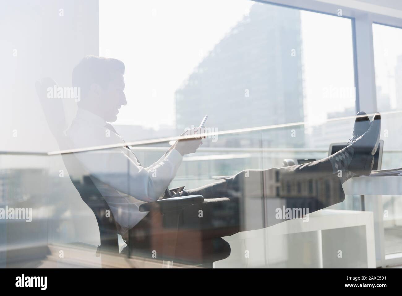 Geschäftsleute nutzen das Smartphone im sonnigen, städtischen Büro Stockfoto