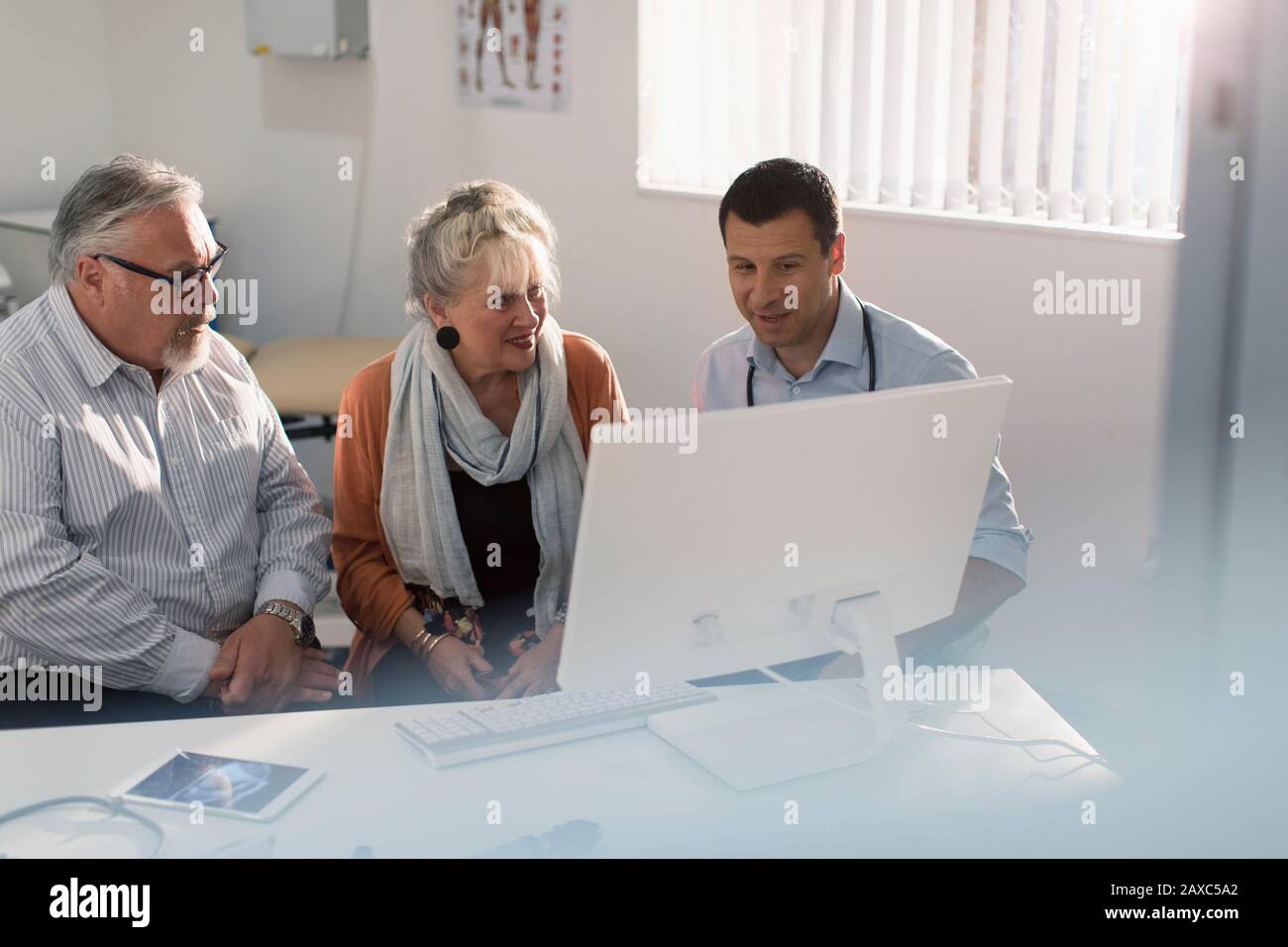 Arztbesprechung mit dem Senioren-Paar am Computer im Arztbüro Stockfoto