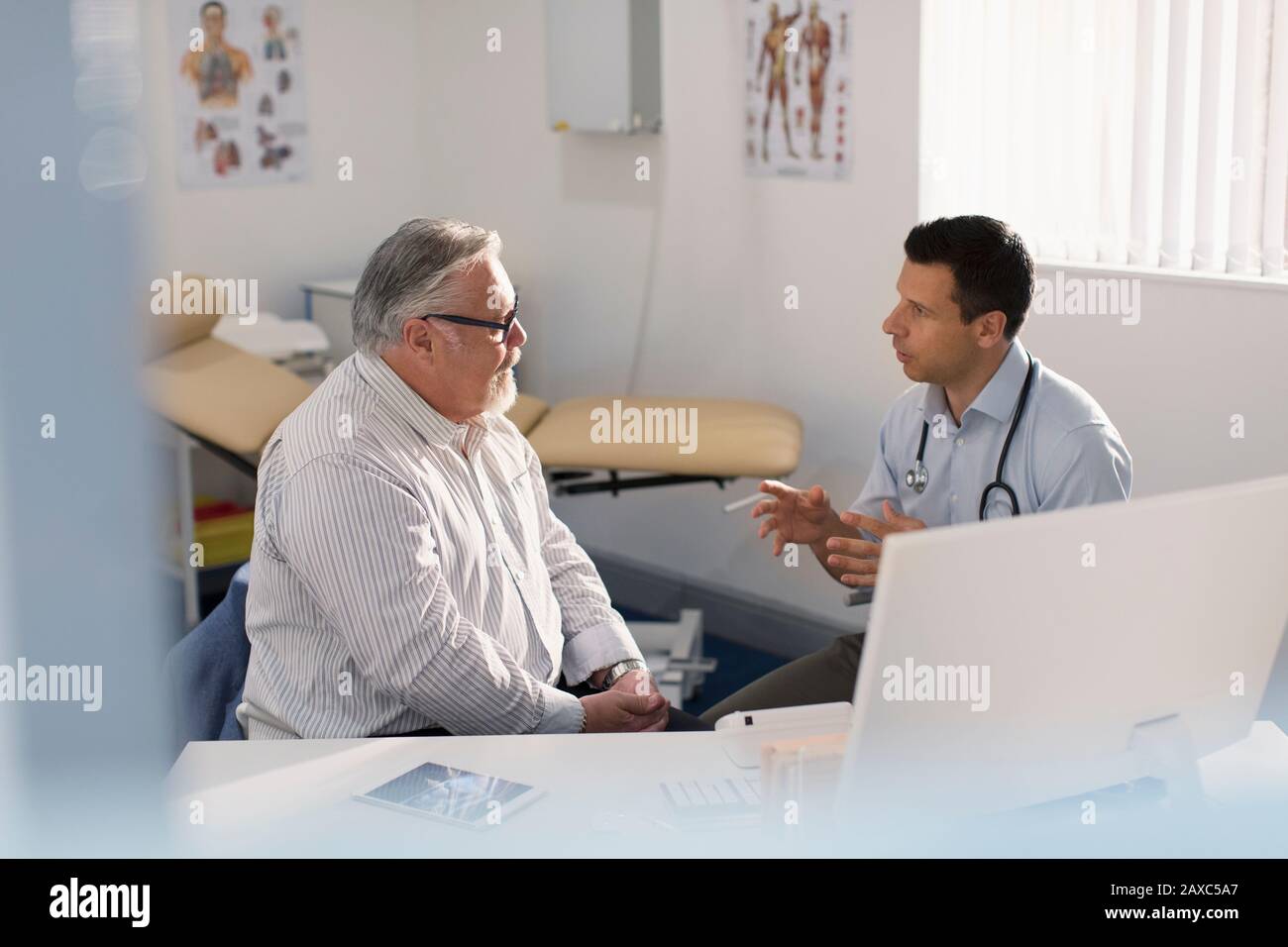 Männlicher Arzt spricht mit dem Patienten in der Arztpraxis Stockfoto