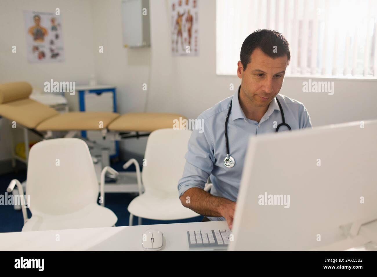 Männlicher Arzt, der am Computer in der Arztpraxis arbeitet Stockfoto