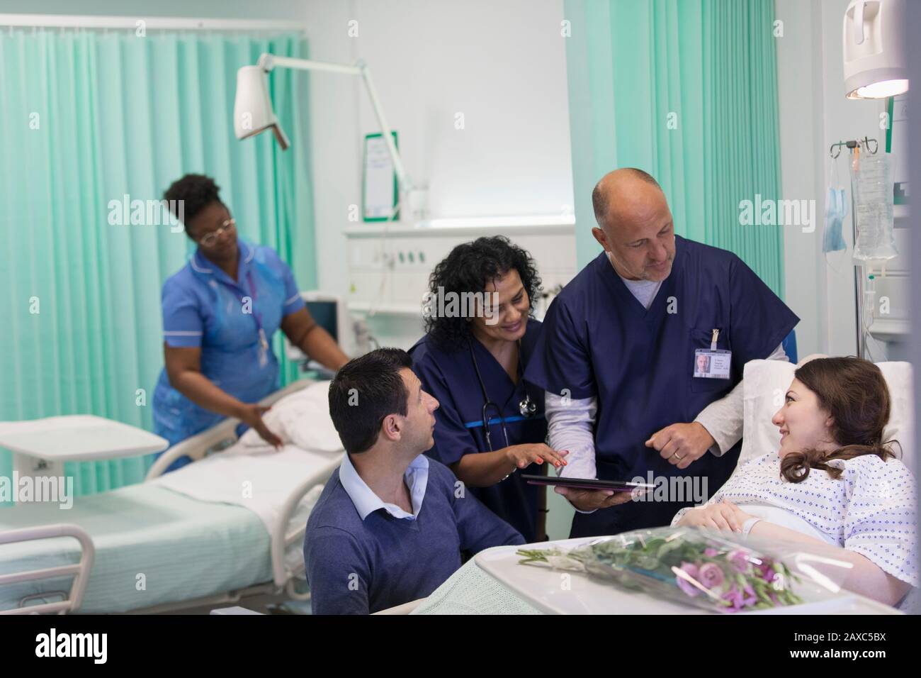 Ärzte mit digitaler Tablette runden das Gespräch mit dem Patienten auf der Krankenstation ab Stockfoto