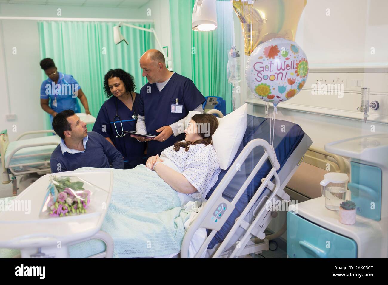 Ärzte machen Runden und sprechen mit einem Paar in der Krankenstation Stockfoto