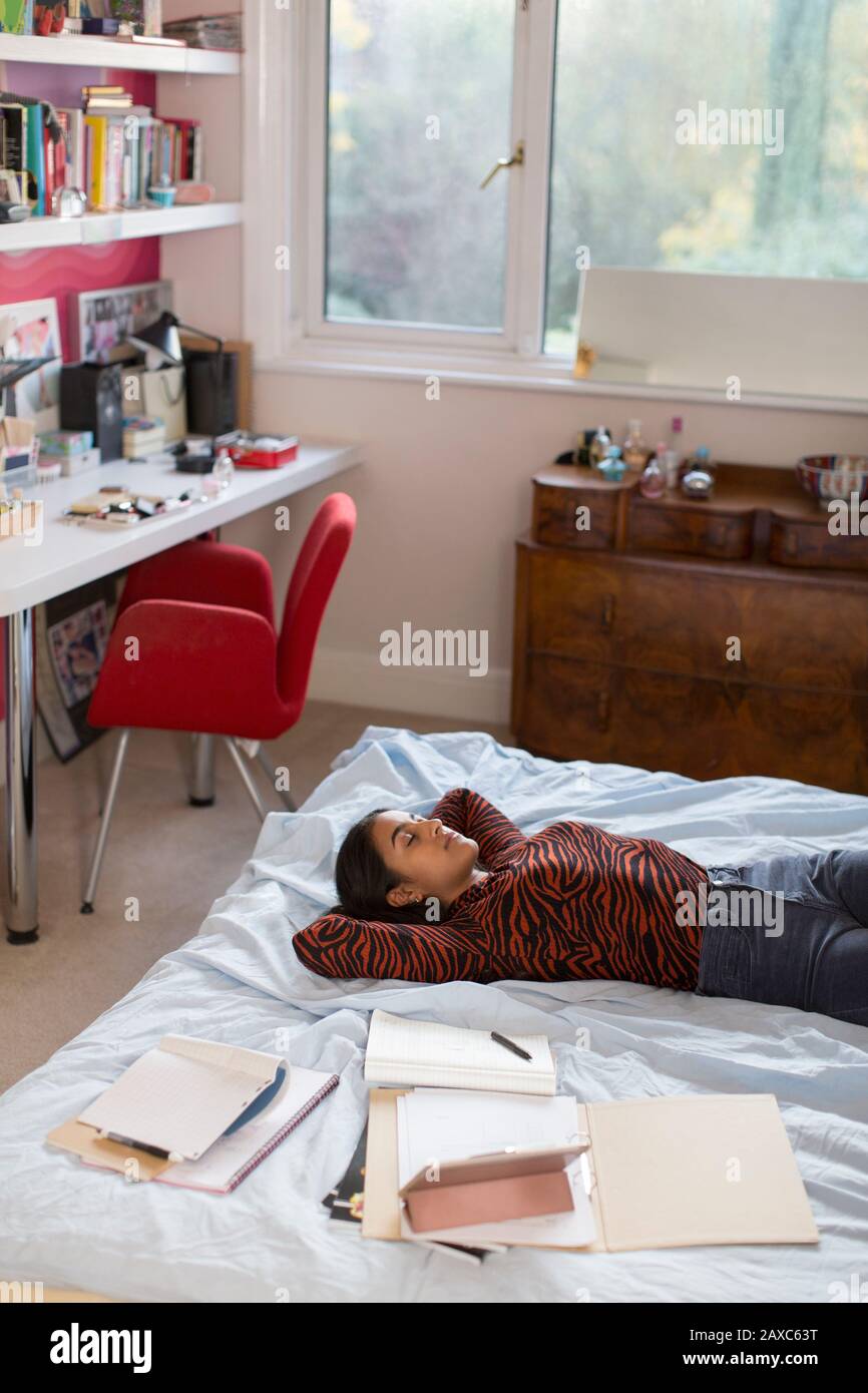 Müde Teenager-Mädchen, die eine Pause vom Studium machen, das auf dem Bett ruht Stockfoto
