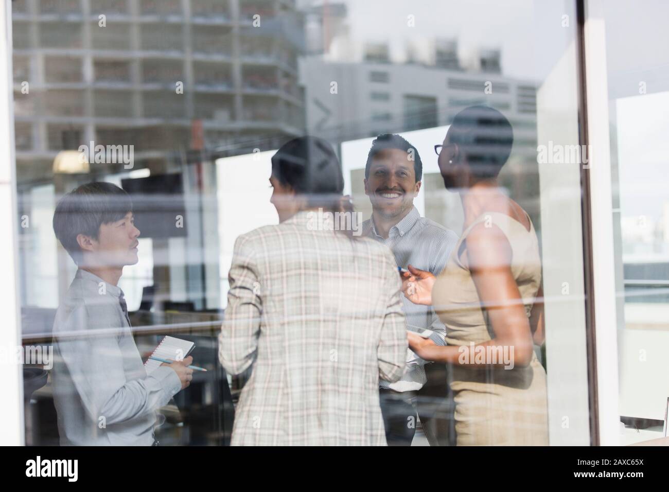 Lächelnde Geschäftsleute, die im sonnigen Bürofenster sprechen Stockfoto