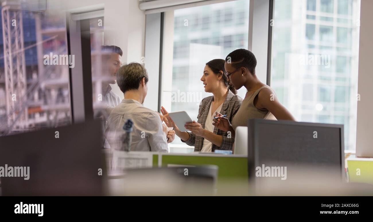 Geschäftsleute, die über digitale Tablets sprechen und sich im Büro treffen Stockfoto