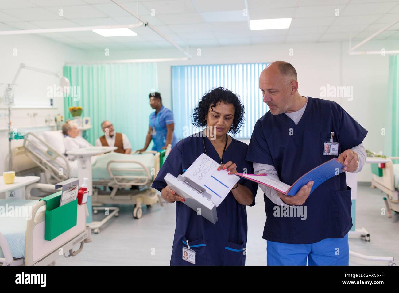 Ärzte mit medizinischen Diagrammen, die Runden kommen, Beratung in der Krankenstation Stockfoto