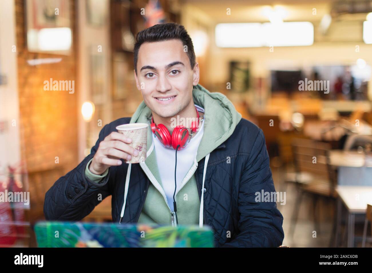 Portrait lächelnd, selbstbewusster junger Student der männlichen Hochschule, der im Café studiert und Kaffee trinkt Stockfoto