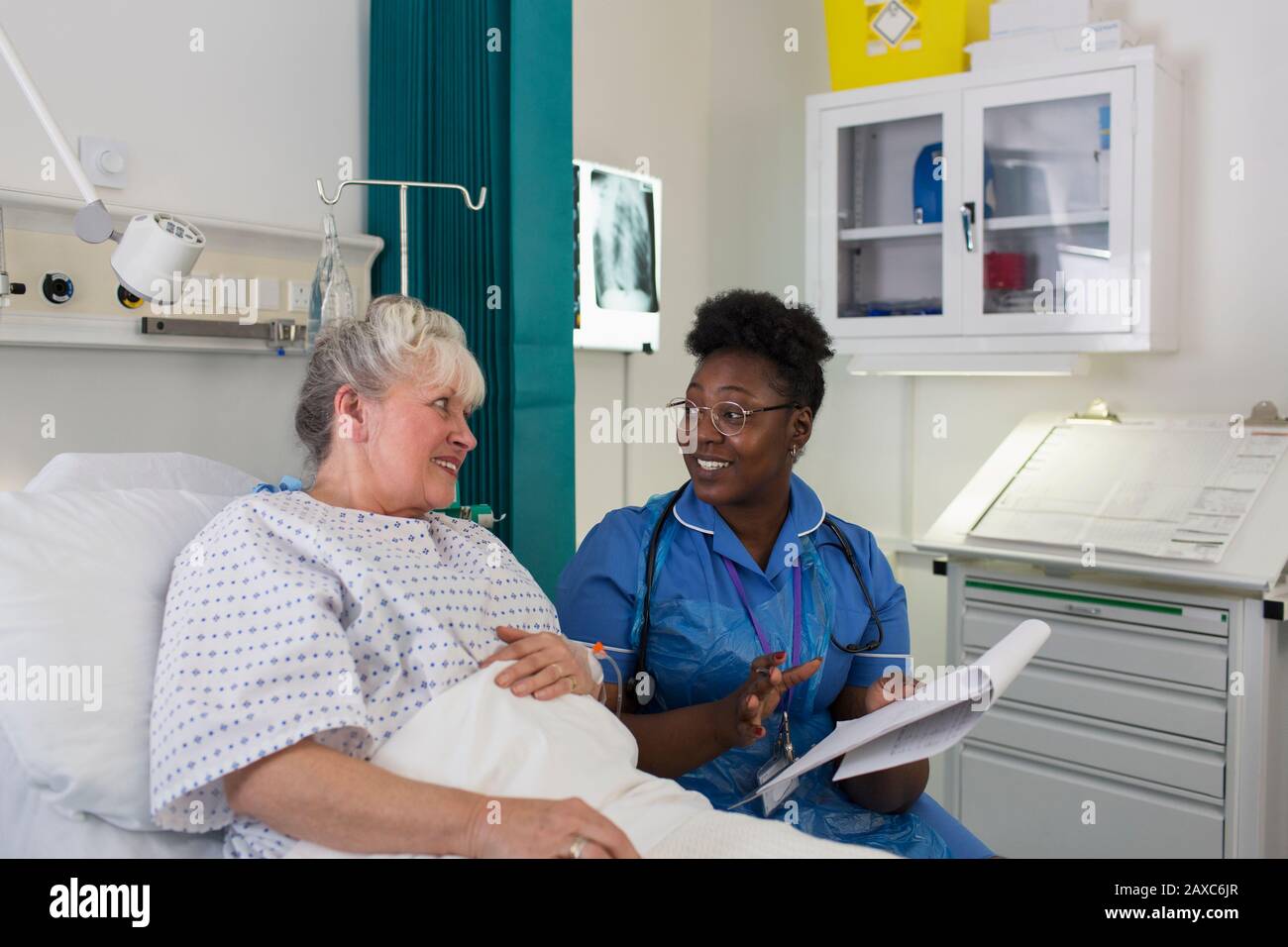 Weibliche Krankenschwester im Krankenhauszimmer mit einer älteren Patientin sprechen Stockfoto