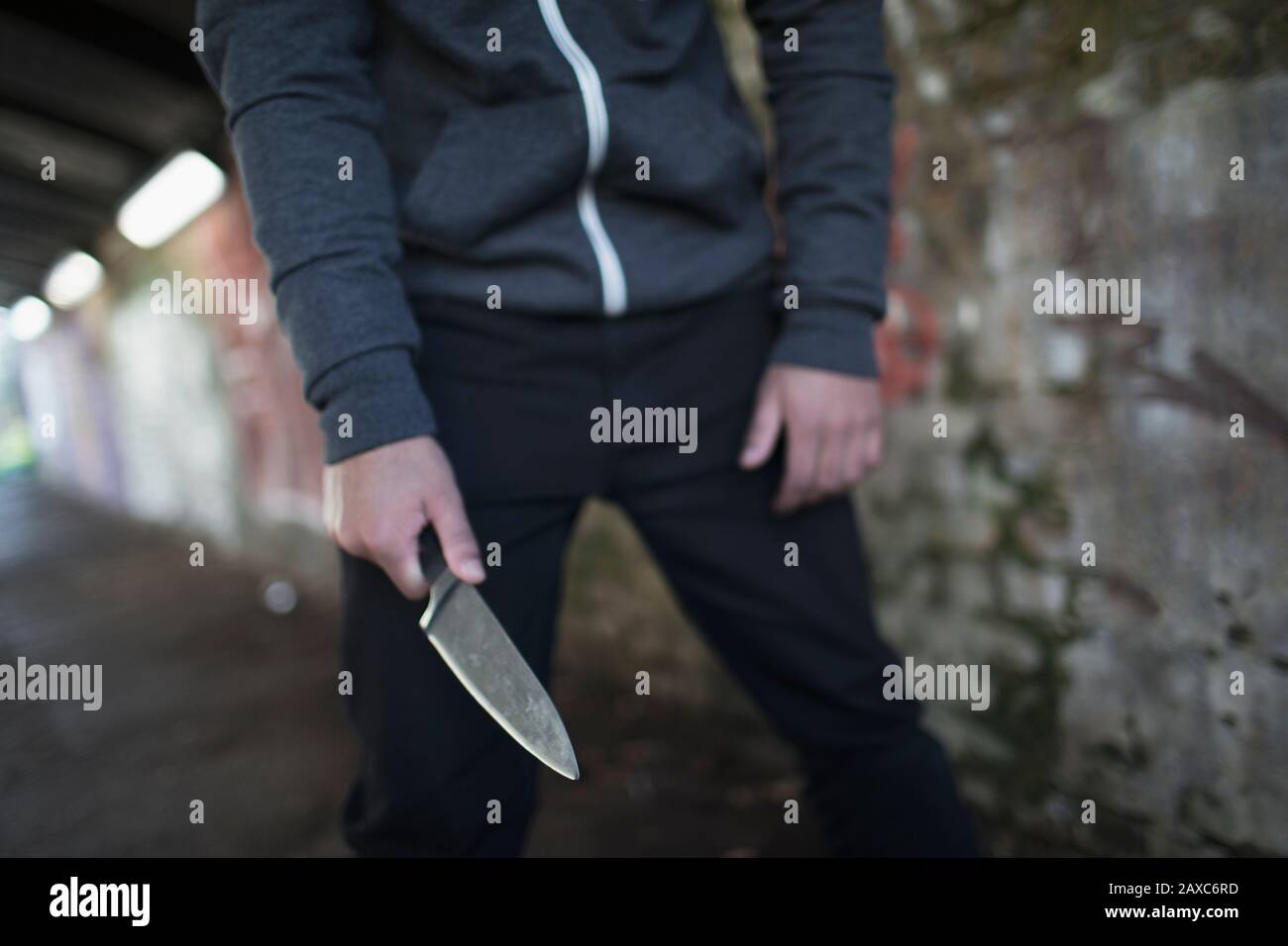 Junger Mann, der die Messerwaffe im Tunnel hält Stockfoto