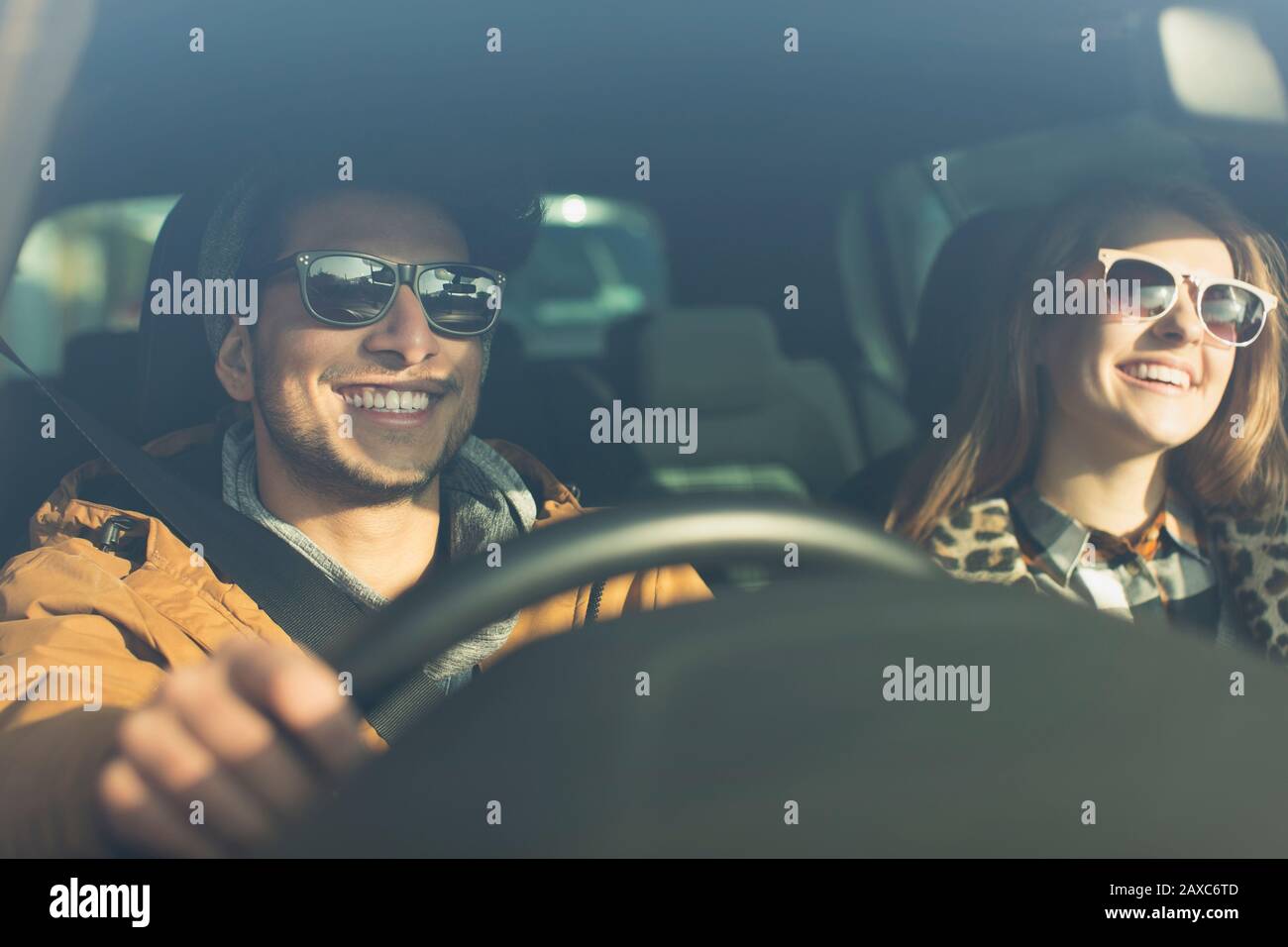 Glückliches junges Paar trägt Sonnenbrille im Auto Stockfoto