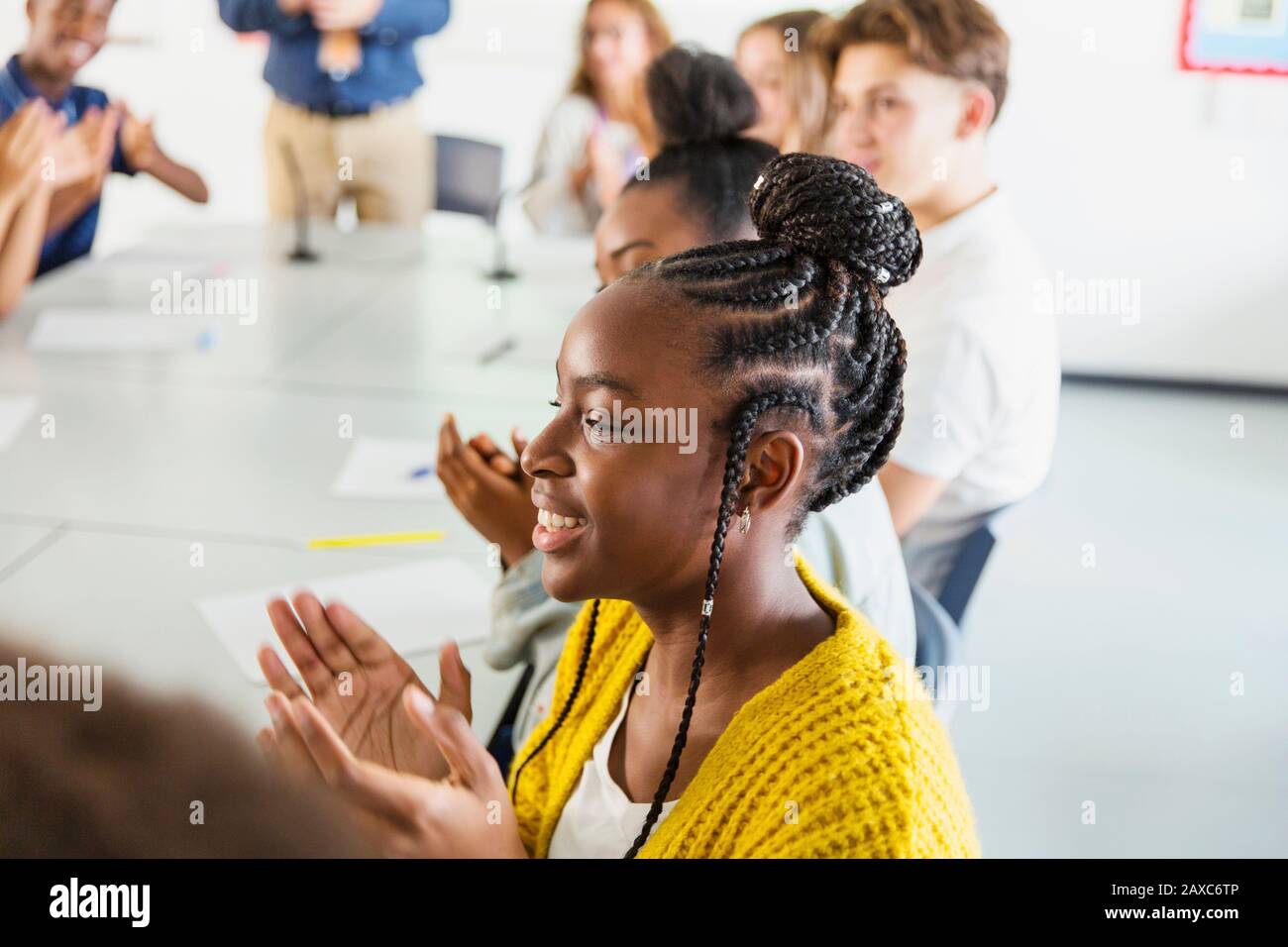 Lächelnde Schüler der High School klatschen im Klassenzimmer Stockfoto