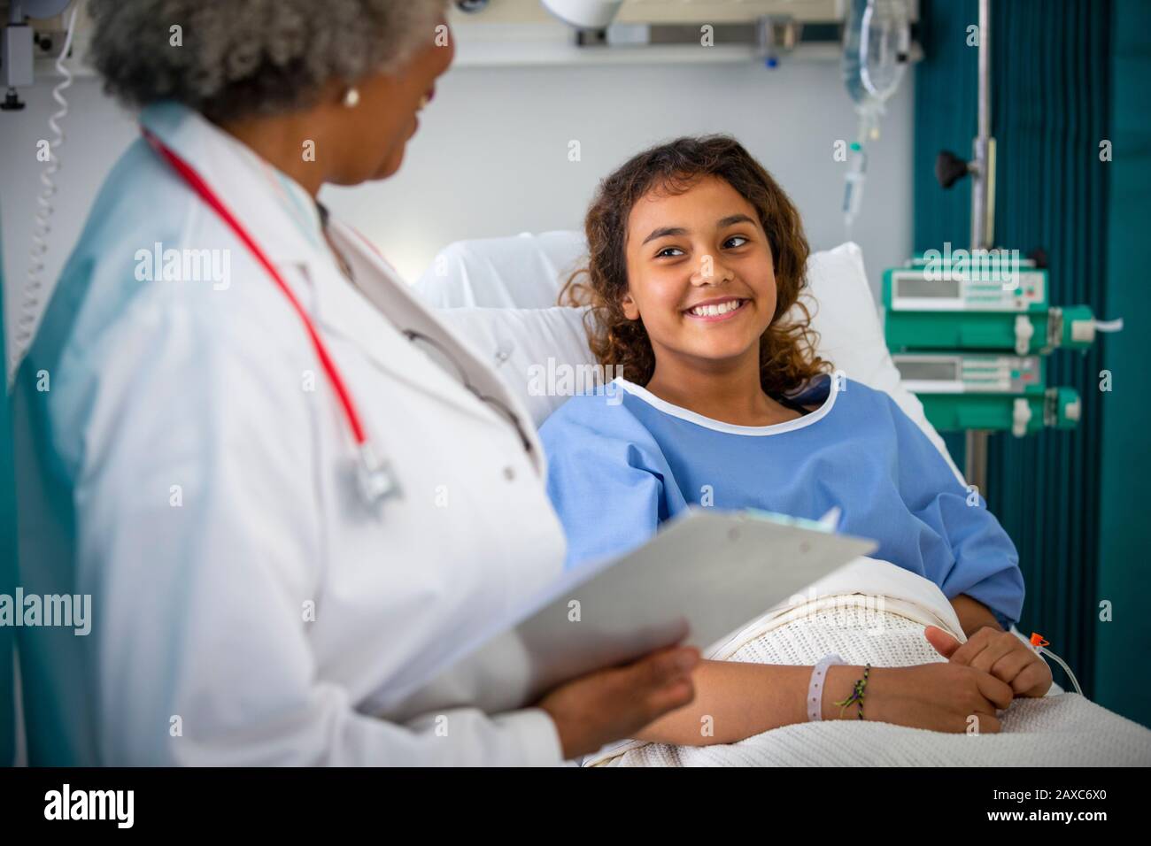 Lächelnde Patientin, die im Krankenhauszimmer mit einem Arzt spricht Stockfoto