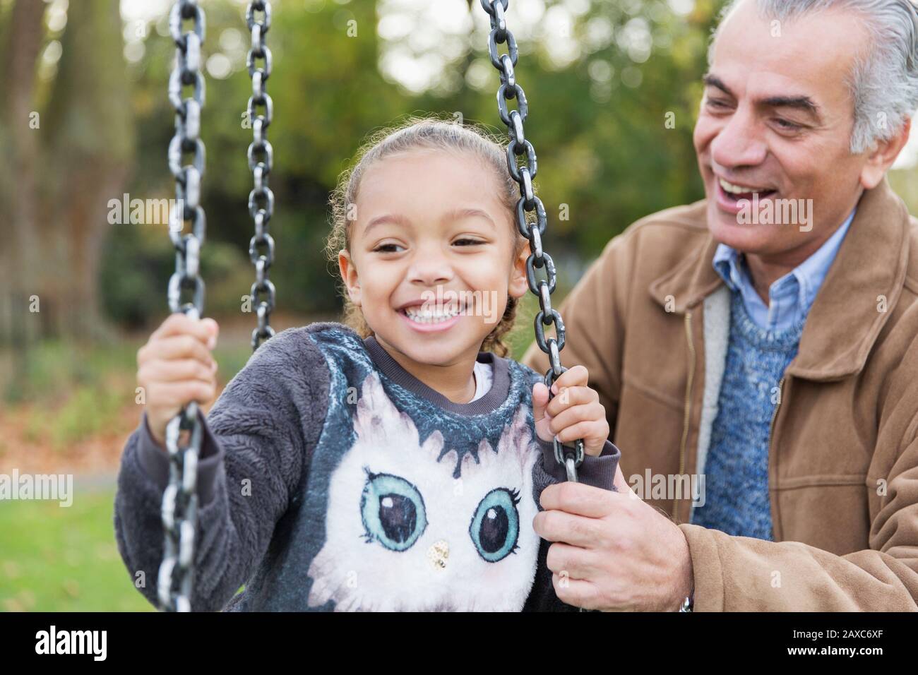 Verspielter Großvater und Enkelin auf Spielplatzschwinge Stockfoto
