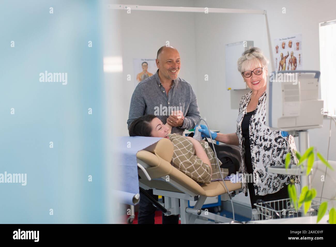 Techniker, der Ultraschall für glückliche schwangere Paare im Untersuchungsraum durchführt Stockfoto