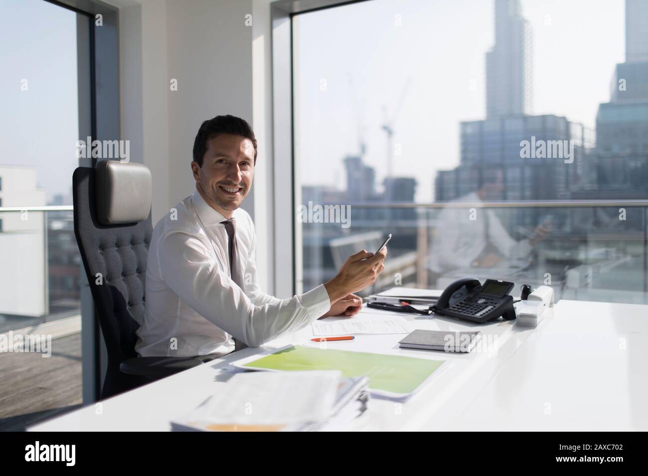 Hochformat selbstbewusster Geschäftsmann mit Smartphone im Hochhaus Stockfoto