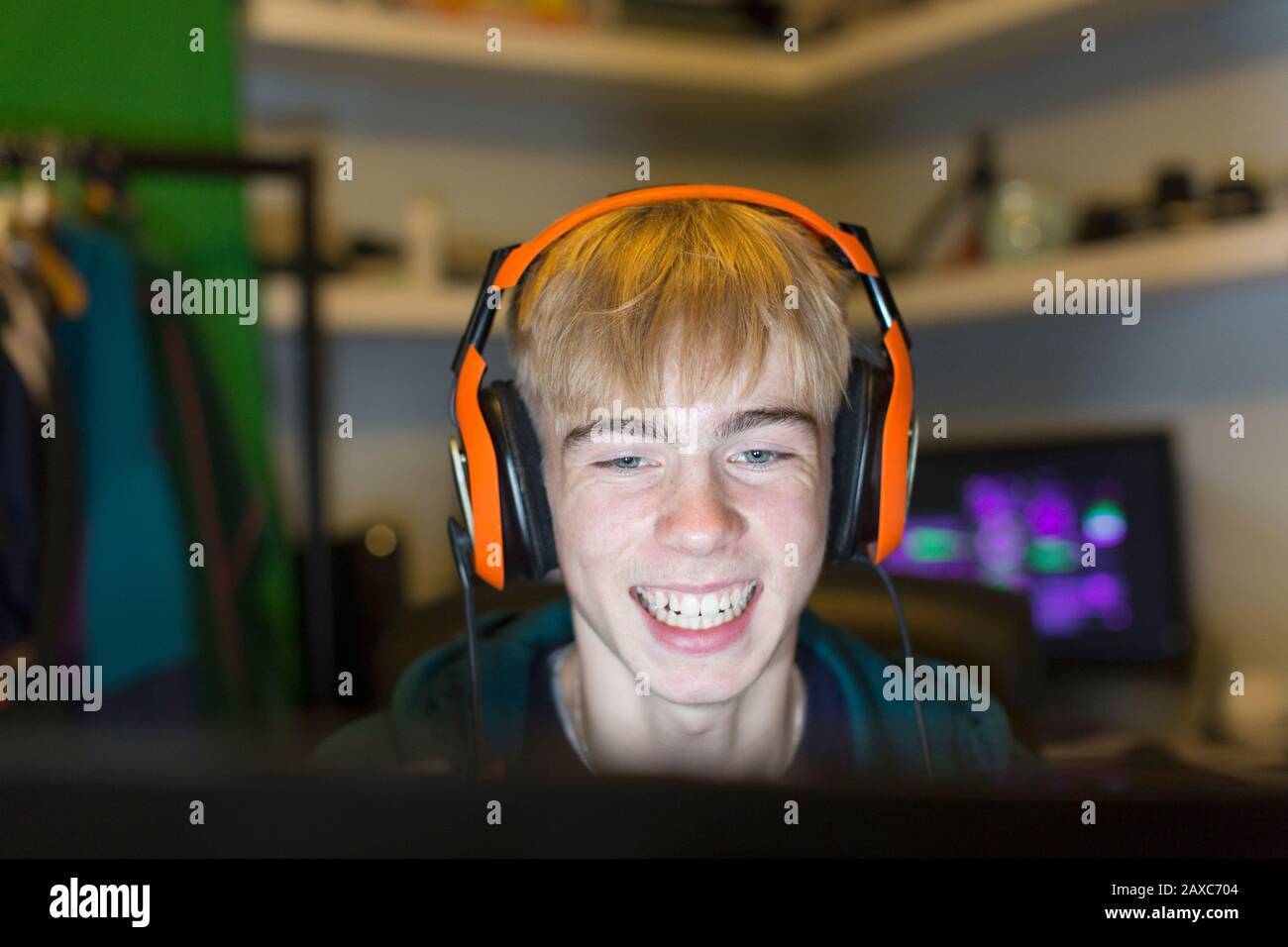 Fröhlicher Teenager mit Headset, das Videospiel am Computer spielt Stockfoto