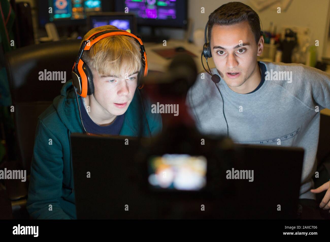 Teenager mit Kopfhörern spielen Videospiel am Computer im dunklen Raum Stockfoto