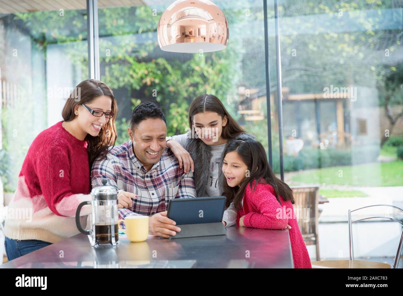 Eine glückliche Familie, die ein digitales Tablet am Küchentisch verwendet Stockfoto