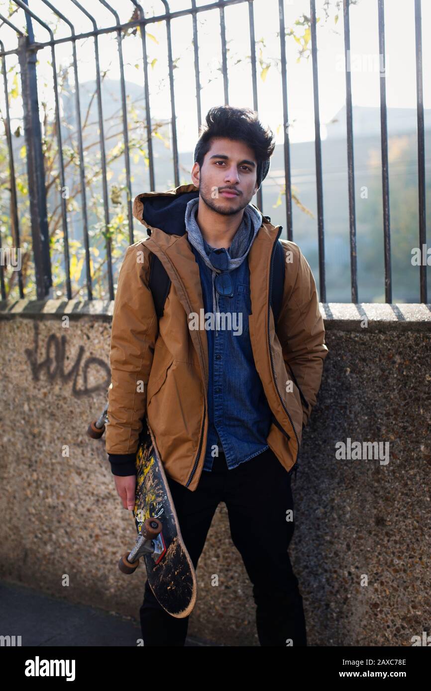 Portrait selbstbewusster junger Mann, der Skateboard hält Stockfoto
