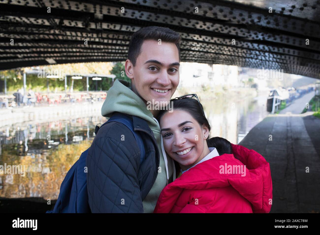 Portrait fröhliches junges Paar, das sich entlang des Kanals umarmt Stockfoto